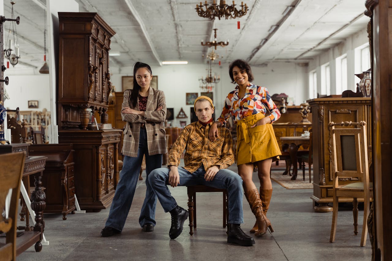 why-choose-us Three stylish adults posing confidently amidst vintage wooden furniture in a store.