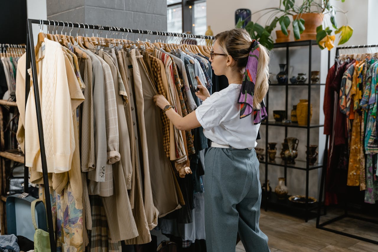 services-02 Woman browsing through clothes on hangers in a stylish boutique setting.